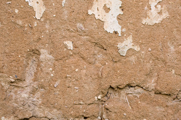 Cracked white paint on a wall of clay. Grunge wall of the old house, textured background