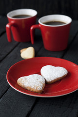 Red cup and cookie hearts on a black background 