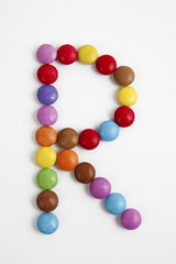 Fototapeta na wymiar La lettera R formata da coloratissimi confetti di cioccolato.