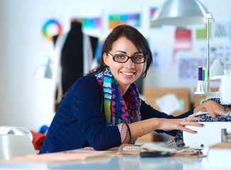 Young woman sewing while sitting at her working place