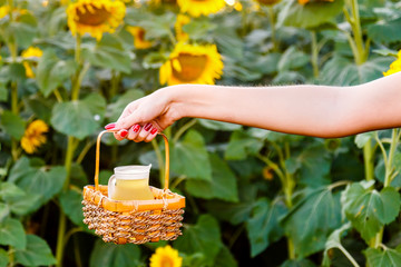 Female hand holding a wicker basket with a jug of sunflower oil