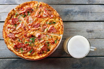 Tasty pizza and glass of beer are on wooden table, close up