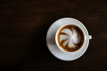 Cup of cappuccino art coffee with froth shape plumeria and woode