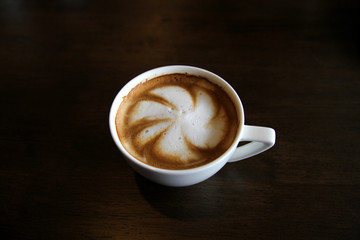 Cup of cappuccino art coffee with froth shape plumeria and woode