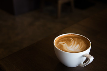 Tasse Latte-Art-Kaffee mit schaumförmigem Vogel und hölzernem Hinterg