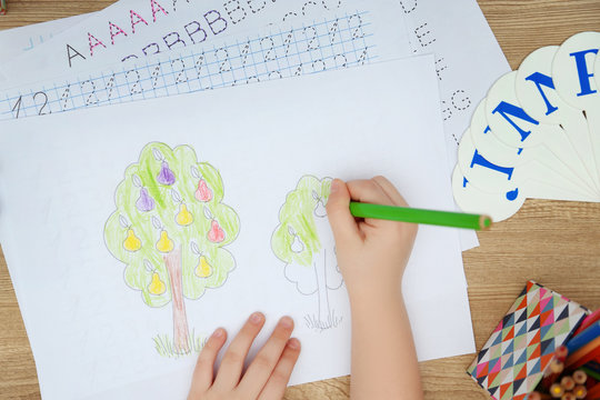 Little girl learning to draw at the table