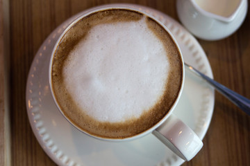 Cup of cappuccino art coffee with froth milk and wooden backgrou