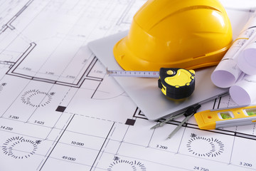 Construction blueprints with tools and helmet closeup