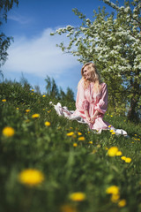 Fototapeta premium beautiful girl in dress sitting under the apple blossom