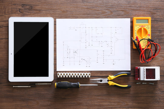 Electrical drawings, tablet and tools on wooden table, top view