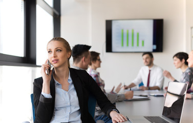 business woman speeking on phone at office with team on meeting