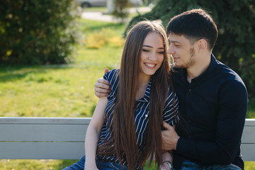 Loving young beautiful couple sitting on the bench hugging with copy space