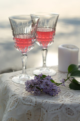 Two glas of pink wine and lilac on the table outdoors