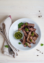 Sliced Steak served in white bowl with chimichurri sauce. Top view.