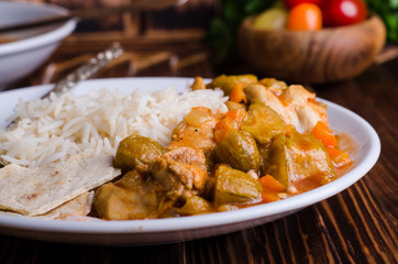 Ragout with chicken and okra or bamia or lady finger in white bowl on wooden background. Selective focus