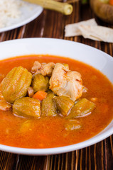 Ragout with chicken and okra or bamia or lady finger in white bowl on wooden background. Selective focus