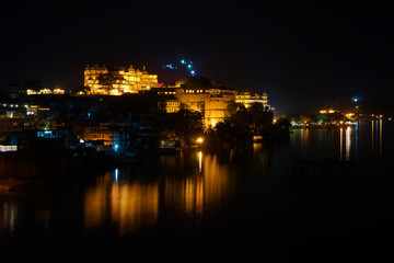 Horizontal panorama of the Udaipur City Palace and Pichola lake on the night with accent lighting,...