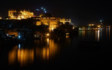 Fototapeta premium Horizontal panorama of the Udaipur City Palace and Pichola lake on the night with accent lighting, Rajasthan, India