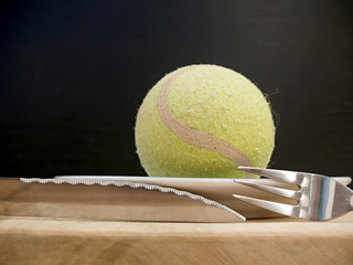 yellow tennis ball and cutlery on abstract still life