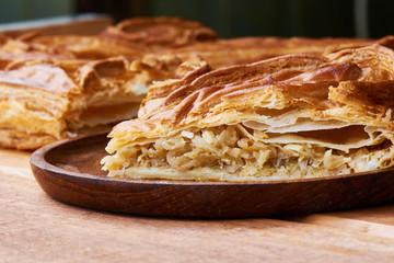 A piece of pie with filling their cabbage on wooden plate