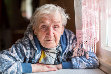 Portrait of an elderly woman sitting at a table in the kitchen.