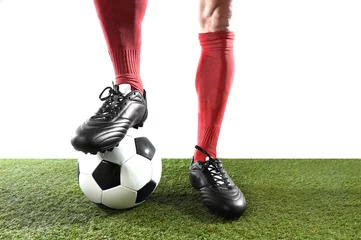 Fototapeten legs feet of football player in red socks and black shoes posing with the ball playing on green grass pitch © Wordley Calvo Stock