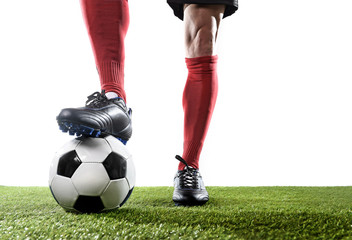legs feet of football player in red socks and black shoes posing with the ball playing on green grass pitch - Powered by Adobe