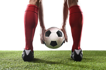 legs of football player in red socks and black shoes holding the ball in his hands placing free kick