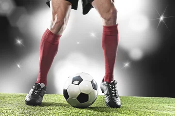 Poster  football player in red socks and black shoes running and dribbling with the ball playing on stadium © Wordley Calvo Stock