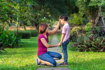 Mother sitting at park holding hands and teaching her son