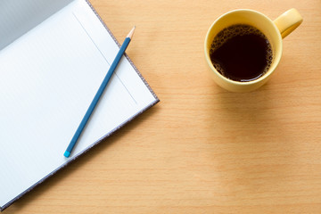 Coffee cup with notebook and pencil.