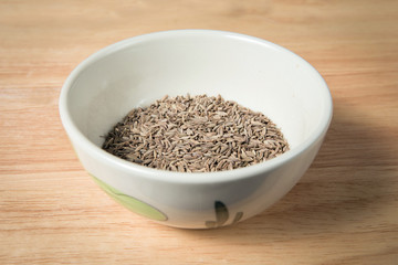 bowl of dried cumin seed on the wood background