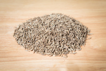 pile of dried cumin seed on the wood background