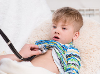 doctor examining boy with stethoscope
