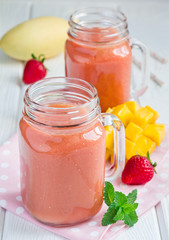 Healthy smoothie with strawberry, mango and banana in glass jars
