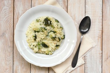 Creamy risotto with broccoli on the cloth and wooden background