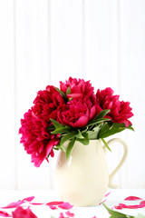 Bouquet of red peony flowers on a white wooden table