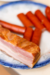 Slice of raw bacon on the plate with sausages