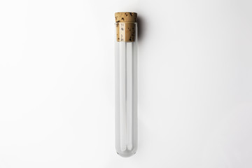 Empty glass transparent test tube closed with cork on white background