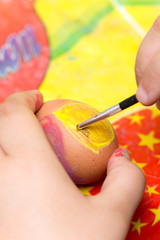 Children's Hand coloring Easter egg with brush and tempera