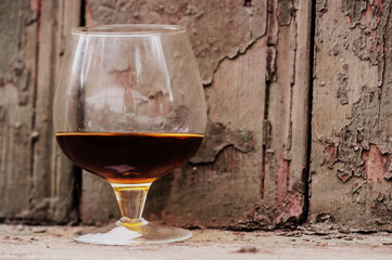 A glass of cognac on the background of the old wooden wall