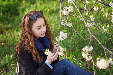 Fototapeta premium young woman in black coat walking in a blossoming spring garden