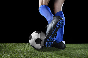  legs and feet of football player in action running and dribbling with the ball playing on green grass