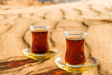  tea in traditional glasses  on desert at sunset