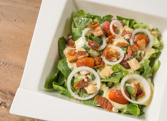 Caesar salad in White plate,Orange juice,Glass of water on woode