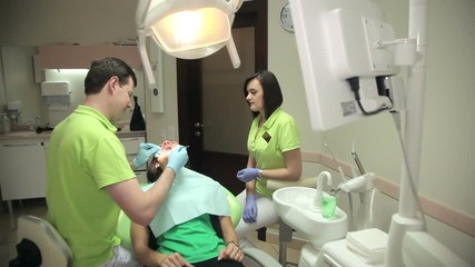 Dentist and assistant treating the patient teeth