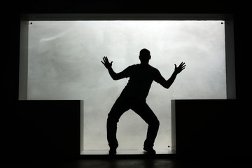 Silhouette of a dancing man in a T-shaped window. Self-portrait.