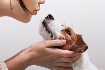 Closeup portrait handsome young hipster woman, kissing her good friend dog on grey background. Positive human emotions, facial expression, feelings