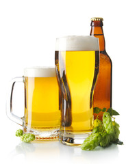 Mugs of beer on table with hop cones isolated on white