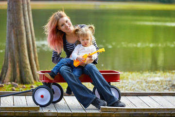 mother and daughter playing toy guitar in a lake